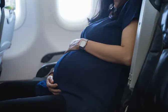 Schwangere Frau mit Koffer am Flughafen Belgrad Nikola Tesla